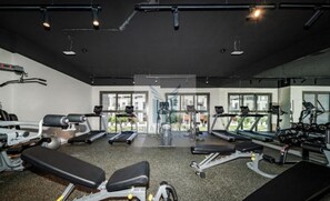 Une salle de sport équipée de tapis de course, d’appareils de musculation et de bancs.