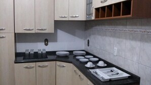 A kitchen with light wood cabinets, a black countertop, and white tiled backsplash. - Amber Sul Hospedagem (Gramado)