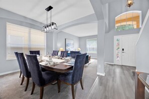 Un espace repas avec une table rectangulaire, des chaises foncées et des luminaires suspendus.