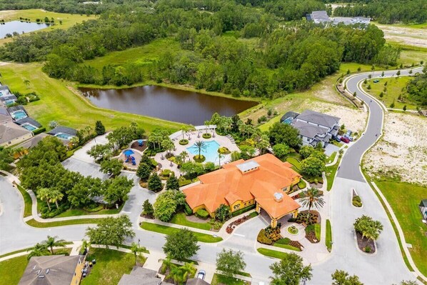 Vue aérienne d’un quartier résidentiel avec une grande maison, une piscine et un lac.