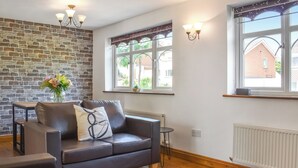 A modern living room with a leather sofa, a small table, and a decorative vase. - 2 bedroom accommodation in Whitby (Whitby)