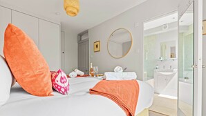Une chambre d’hôtel moderne dotée d’un grand lit, d’un miroir rond, d’une salle de bain avec une douche en verre et d’une vue sur la ville.