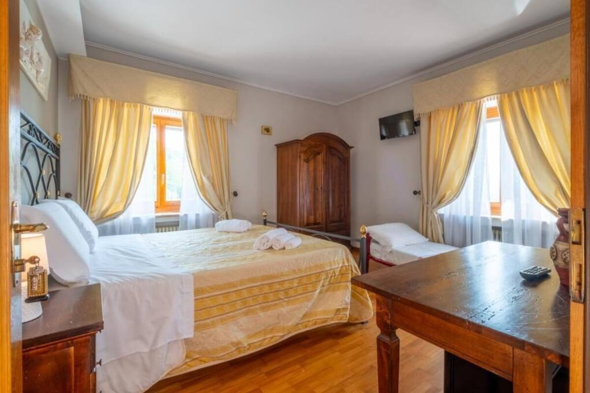 Een hotelkamer met een groot bed, twee nachtkastjes, een houten garderobe en een televisie aan de muur.