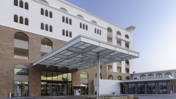 Un hôtel moderne doté d’un grand auvent à l’entrée, de fenêtres en arc de cercle et d’une cour dallée.