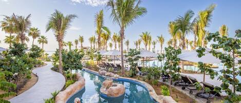 A pool area with lounge chairs and umbrellas, surrounded by palm trees.