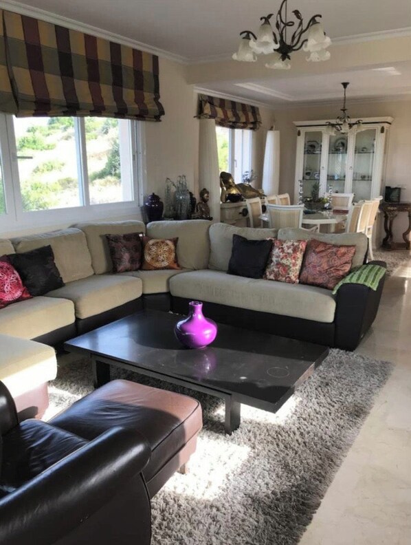 A living room with a sectional sofa, a coffee table, and a chandelier. - Boutique Hotel Mar (Marbella)