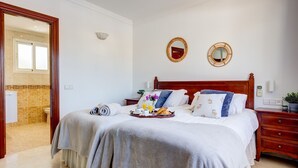 Habitación de hotel con una cama, mesitas de noche, un espejo y un baño visible a través de una puerta abierta.