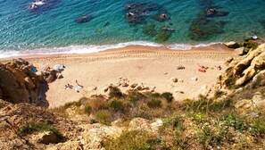 A beach with clear turquoise water, rocky cliffs, and a sandy shore.
