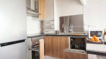 Een moderne keuken met houten kastjes, roestvrijstalen apparatuur en een geïntegreerde vaatwasser.