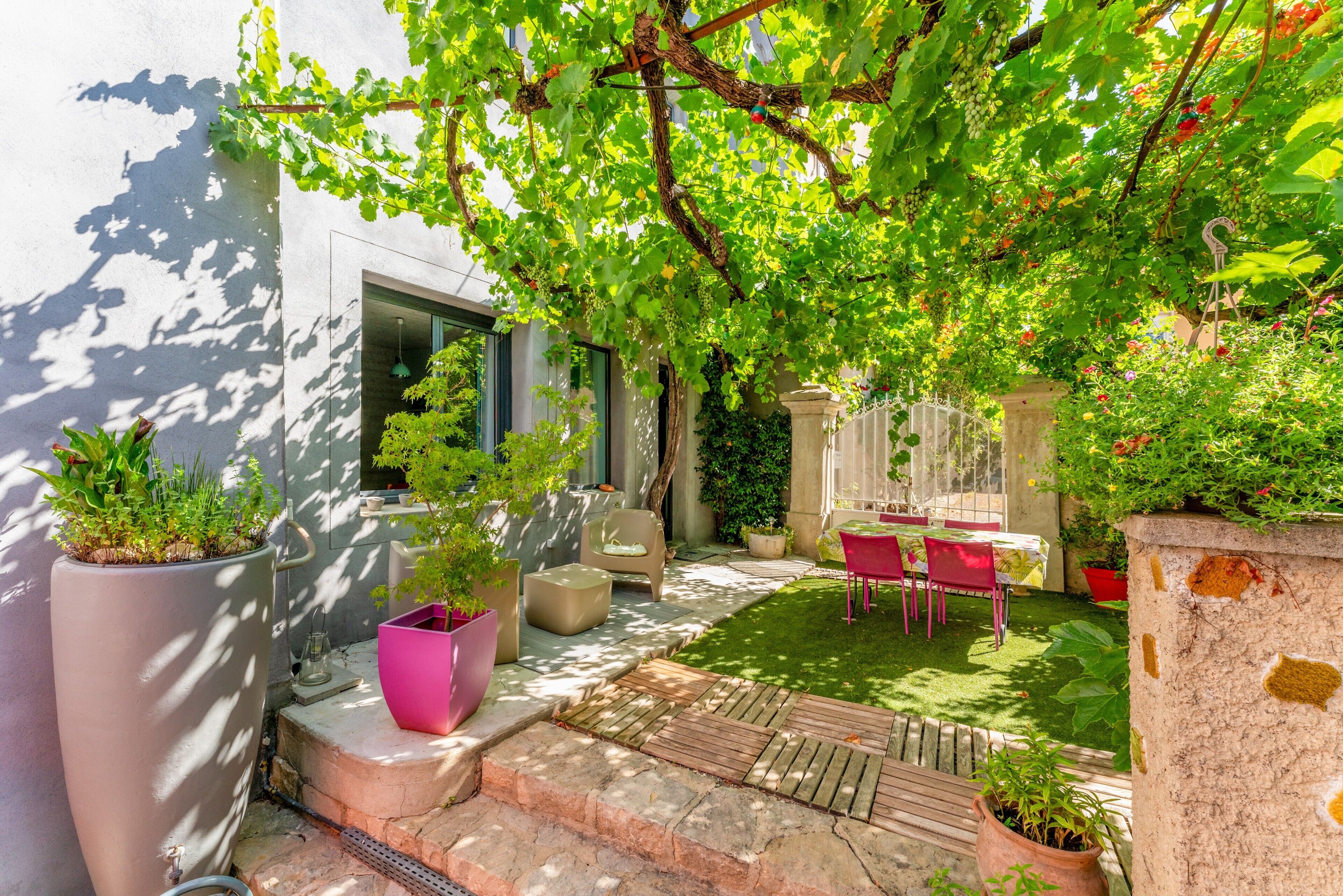 A garden patio with a pergola, potted plants, and outdoor furniture.