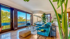 A spacious living room with a large sofa set, a coffee table, and a view of a balcony with a railing. - Skylife Peacock Penthouse (Roma)