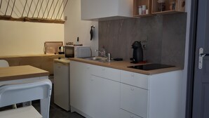 Une cuisine compacte dotée d’un plan de travail blanc, d’un four encastré, d’un four à micro-ondes et d’une machine à café.