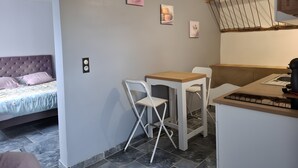Une chambre comprenant un lit, une petite table avec des chaises et un coin cuisine avec un comptoir en bois.