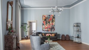 Un salon moderne avec un canapé gris, une console en marbre, une grande peinture abstraite et une bibliothèque noire au design original.