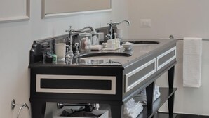 Une salle de bain moderne avec un meuble-lavabo noir et blanc, un grand miroir, deux lampes fixées au mur, un lavabo et un bidet.