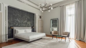 Une chambre à coucher moderne avec un grand lit, une table de chevet, une chaise, un miroir et un lustre.