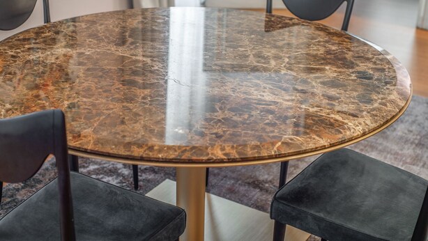Una mesa redonda con tapa de mármol rodeada de cuatro sillas negras.