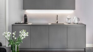 Una cocina moderna con cafetera integrada, hervidor y un televisor de pantalla plana grande montado sobre la encimera.