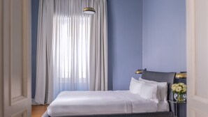 Un dormitorio con una cama, una mesita de noche, una lámpara y un florero con flores.