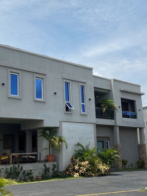A modern building with a flat roof, multiple windows, and a balcony.