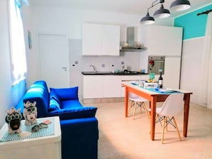 Um espaço compacto com cozinha americana, área de refeições e um sofá.