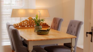 A dining table with four chairs, a lamp, and a decorative plant. - Game Cottage (Bridgnorth)