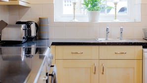 A kitchen with a toaster, a coffee maker, and a sink. - Coachmans Cottage (Bridgnorth)