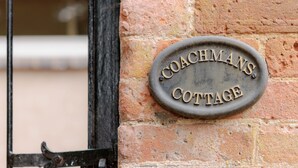 A metal plaque on a brick wall with the inscription "COACHMAN'S COTTAGE". - Coachmans Cottage (Bridgnorth)