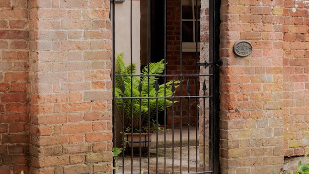 A brick wall with a metal gate and a sign that reads "Torchmans Cottage". - Coachmans Cottage (Bridgnorth)