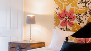 A neatly made bed with white bedding, a black and yellow pillow, and a lamp on a wooden side table. - Coachmans Cottage (Bridgnorth)