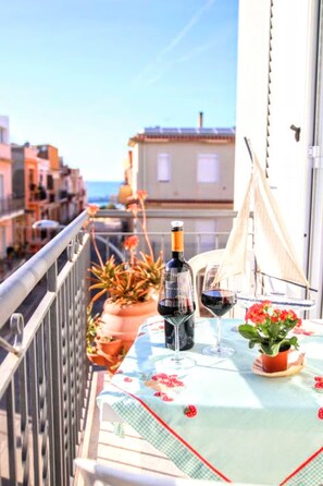 A balcony with a table set for two, potted plants, and a bottle of wine. - Apartment 'L'airone' with Sea View, Wi-Fi and Air Conditioning (Balestrate)