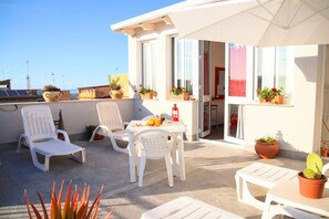 A balcony with white chairs, a table, and potted plants. - Apartment 'L'airone' with Sea View, Wi-Fi and Air Conditioning (Balestrate)