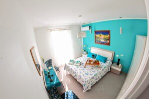 A bedroom with a bed, bedside tables, a nightstand, a window, and a painting on the wall. - Apartment 'L'airone' with Sea View, Wi-Fi and Air Conditioning (Balestrate)