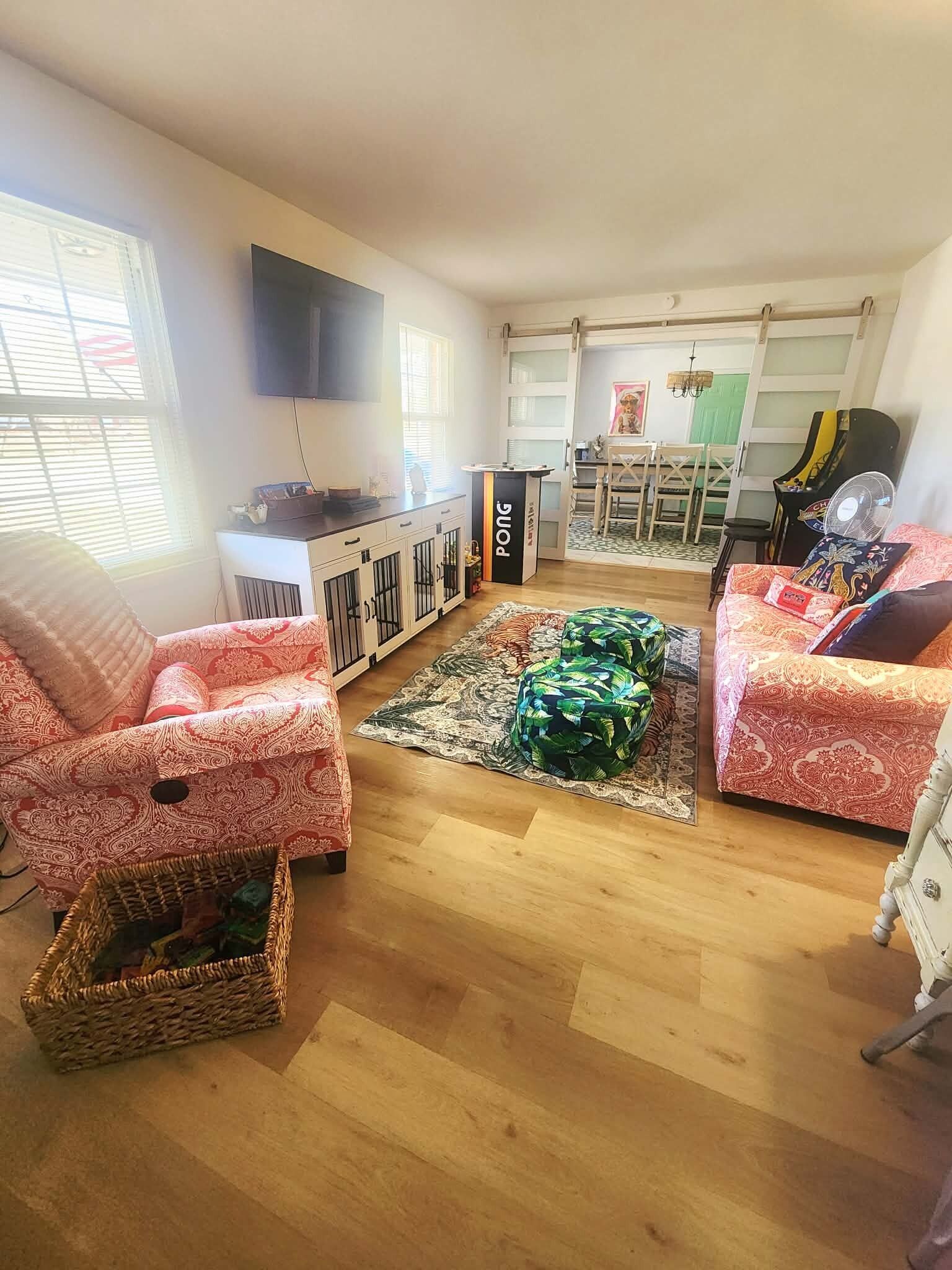Een woonkamer met een bank, een fauteuil, een televisie, een piano en een eethoek.