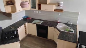 Een kleine keuken met een gasfornuis, een spoelbak en een aanrecht.