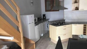 Een kleine keuken met een koelkast, wasmachine en fornuis.