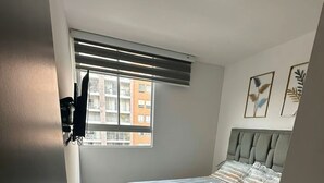 A bedroom with a bed, a window with blinds, a radiator, and a door. - FURNISHED APARTMENT NEAR INTERNATIONAL HOSPITAL FOR RENT RENTAHOSUE (Floridablanca)
