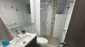 A modern bathroom with a white sink, a toilet, a glass shower enclosure, and a mirror. - FURNISHED APARTMENT NEAR INTERNATIONAL HOSPITAL FOR RENT RENTAHOSUE (Floridablanca)
