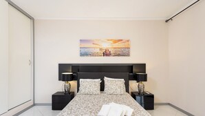 A modern hotel room with a large bed, two bedside tables with lamps, a painting of a sunset over water, and a wardrobe. - Home2Book Apart with Terrace & Pool in Costa Adeje (Adeje)