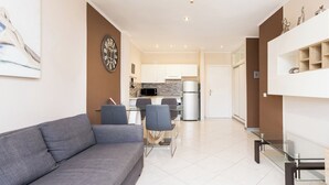 A modern living room with a grey sofa, a glass coffee table, and a dining area with chairs and a table. - Home2Book Apart with Terrace & Pool in Costa Adeje (Adeje)