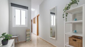 A hallway with a white bench, a potted plant, a mirror, and a shelf with baskets. - Home2Book Charming Rooftop Vibes Apartment (Santa María de Guía)