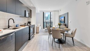 Una cocina moderna con armarios oscuros, lavavajillas de acero inoxidable y un amplio ventanal con vistas a la ciudad.