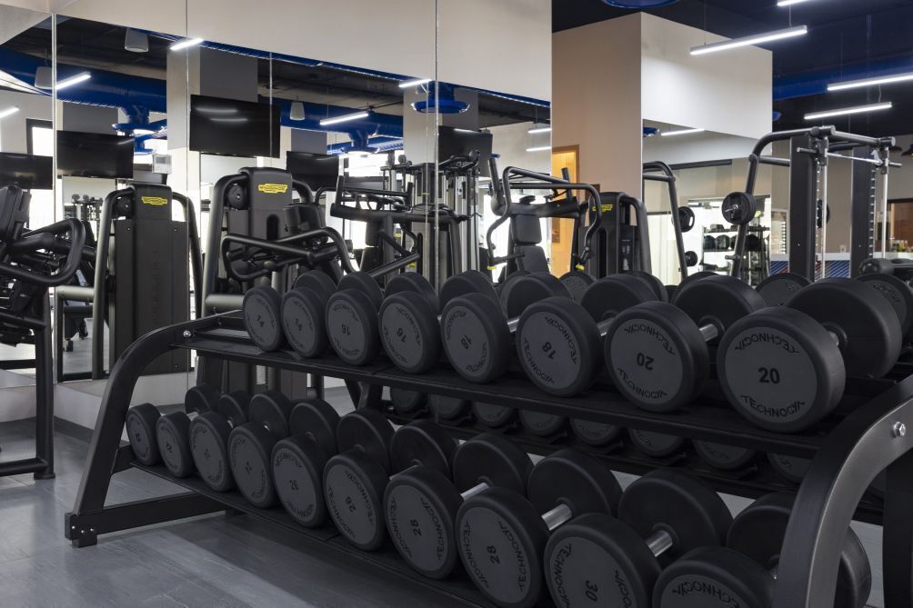 A gym with weightlifting equipment and dumbbells.