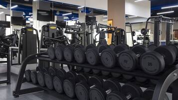 A gym with weightlifting equipment and dumbbells.