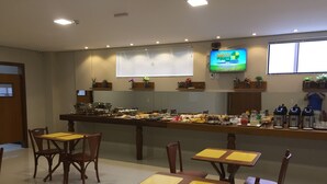 A buffet setup with multiple tables and chairs, a television mounted on the wall, and various food items displayed. - Sonus Hotel (Sinop)