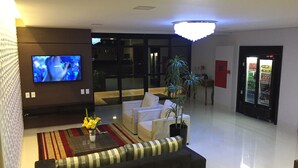 A modern living room with a flat-screen TV, a sofa, a coffee table with flowers, and a plant. - Sonus Hotel (Sinop)