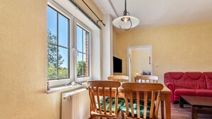 A dining area with a table, chairs, and a window with a view of trees.