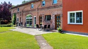 A brick building with a patio area, outdoor seating, and a well-maintained lawn.