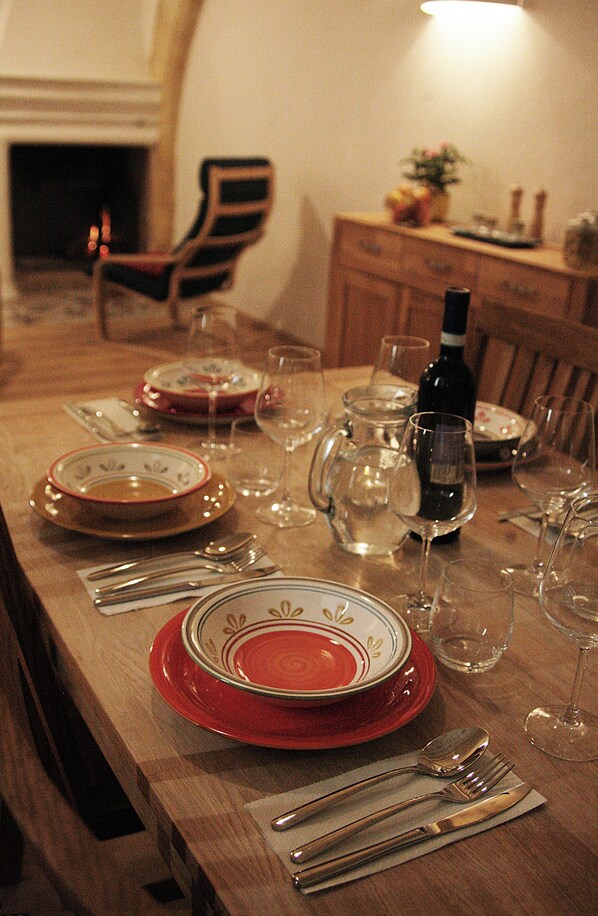 Una mesa de comedor dispuesta con platos, vasos y cubiertos, con una botella de vino y una jarra encima.