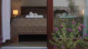 Un dormitorio con cama, mesita de noche, lámpara y ventana que ofrece vistas a flores y un árbol.